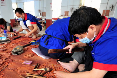 戴著防塵口罩正在木雕的家具廠工人